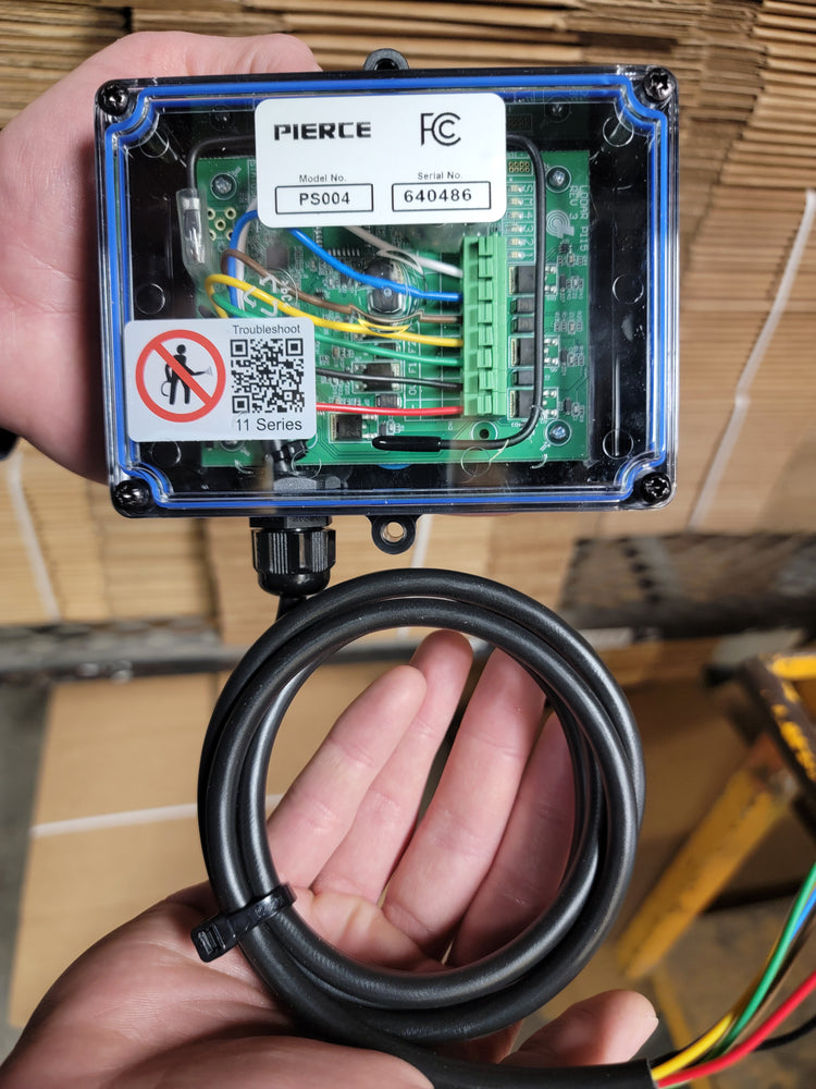 A person holds a PIERCE electronic device, showcasing its circuit board and wires. This advanced 4 Function Wireless Remote Control System integrates smoothly with 12/24V equipment for versatile use.